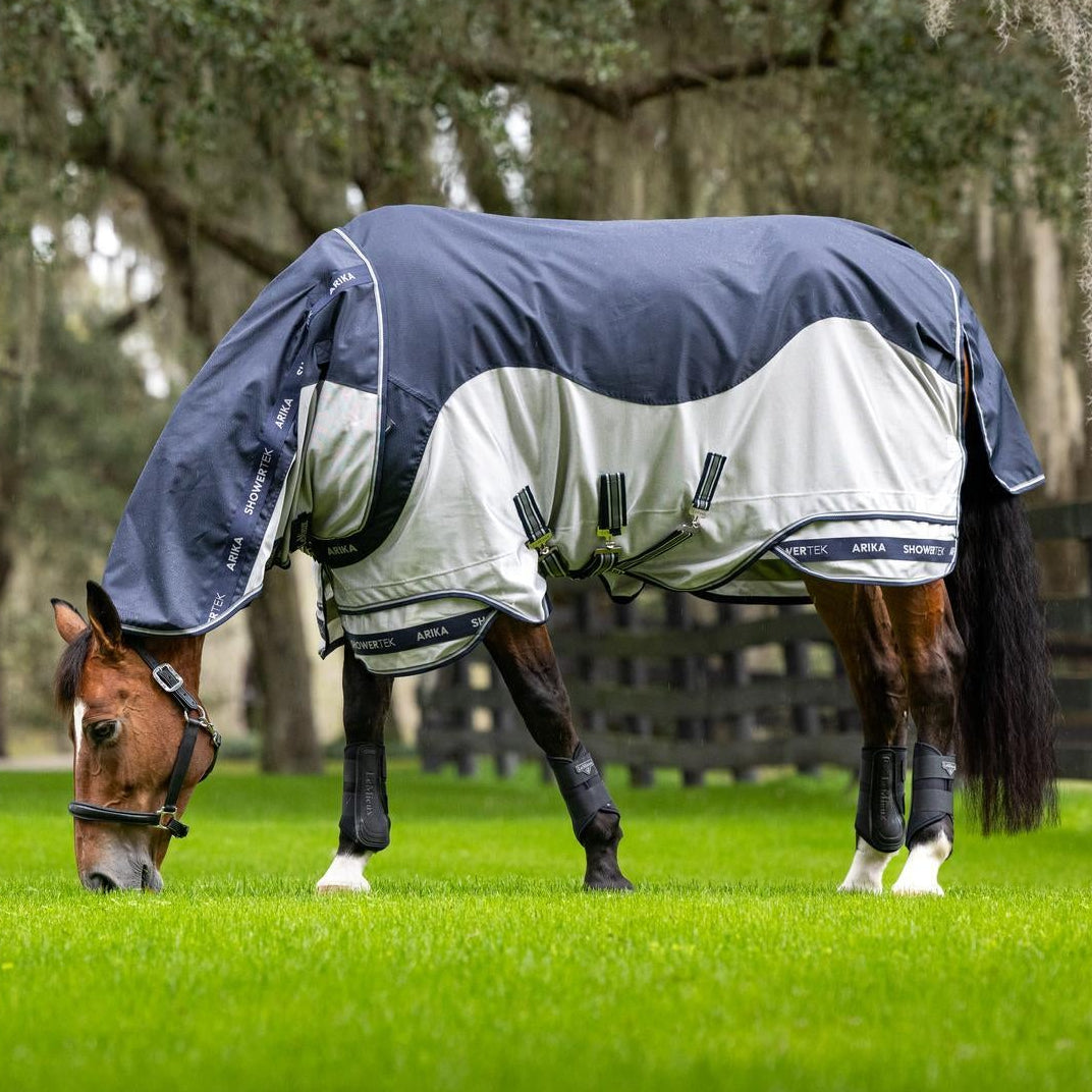 Ein grasendes Pferd auf der Weide zeigt die maximale Bewegungsfreiheit der LeMieux Arika Shower-Tek Fliegendecke Navy, deren patentiertes zweiteiliges Saum-Design Materialspannungen im Brustbereich verhindert und durch das konturierte, abnehmbare Halsteil mit wasserdichtem Mähnenschutz auch bei gesenktem Kopf optimalen Schutz vor Insekten und wechselhaftem Wetter bietet.