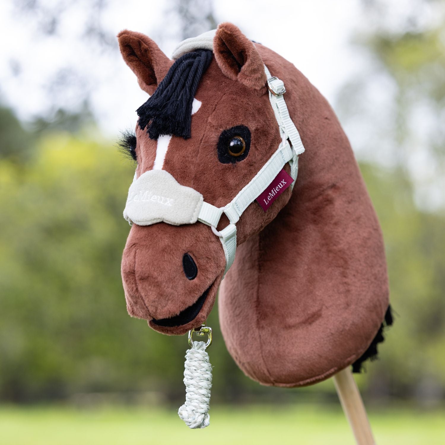 LeMieux Steckenpferd Hobby Horse Chancer mit hellem Hobby Horse Halfter und eingerolltem Führstrick. Die detailgenauen Wimpern lassen Chancer sanft und echt wirken. Das braune Plüsch sieht weich aus.