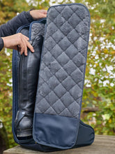 Reiterin stellt ihre Reitstiefel in die LeMieux Stiefeltasche Luxe Navy und trennt sie durch die gepolsterte Innenwand – luxuriöser Schutz für Lederreitstiefel.