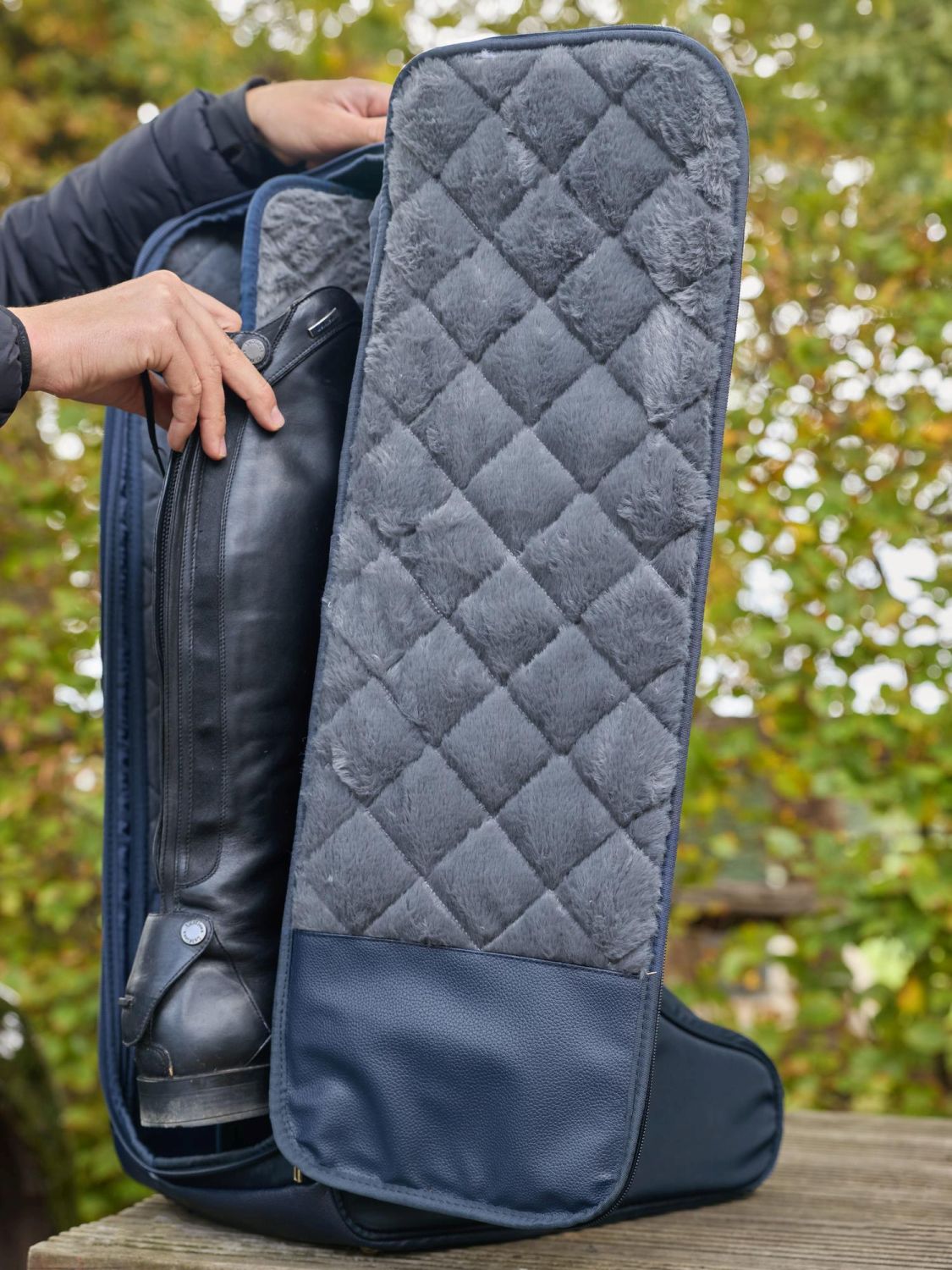 Reiterin stellt ihre Reitstiefel in die LeMieux Stiefeltasche Luxe Navy und trennt sie durch die gepolsterte Innenwand – luxuriöser Schutz für Lederreitstiefel.