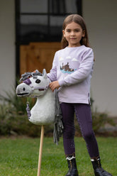 Kind mit LeMieux Hobby Horse Earl Dressur im Freien. Kind spielt mit Hobby Horse im Garten.