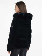 Rückansicht der LeMieux Aspen Puffer Jacket Black – taillierte schwarze Steppjacke mit abnehmbarer Kapuze. Model trägt die Steppjacke Aspen und zeigt diese in seitlicher Rückansicht. LeMieux Logo am Arm ist zu erkennen.