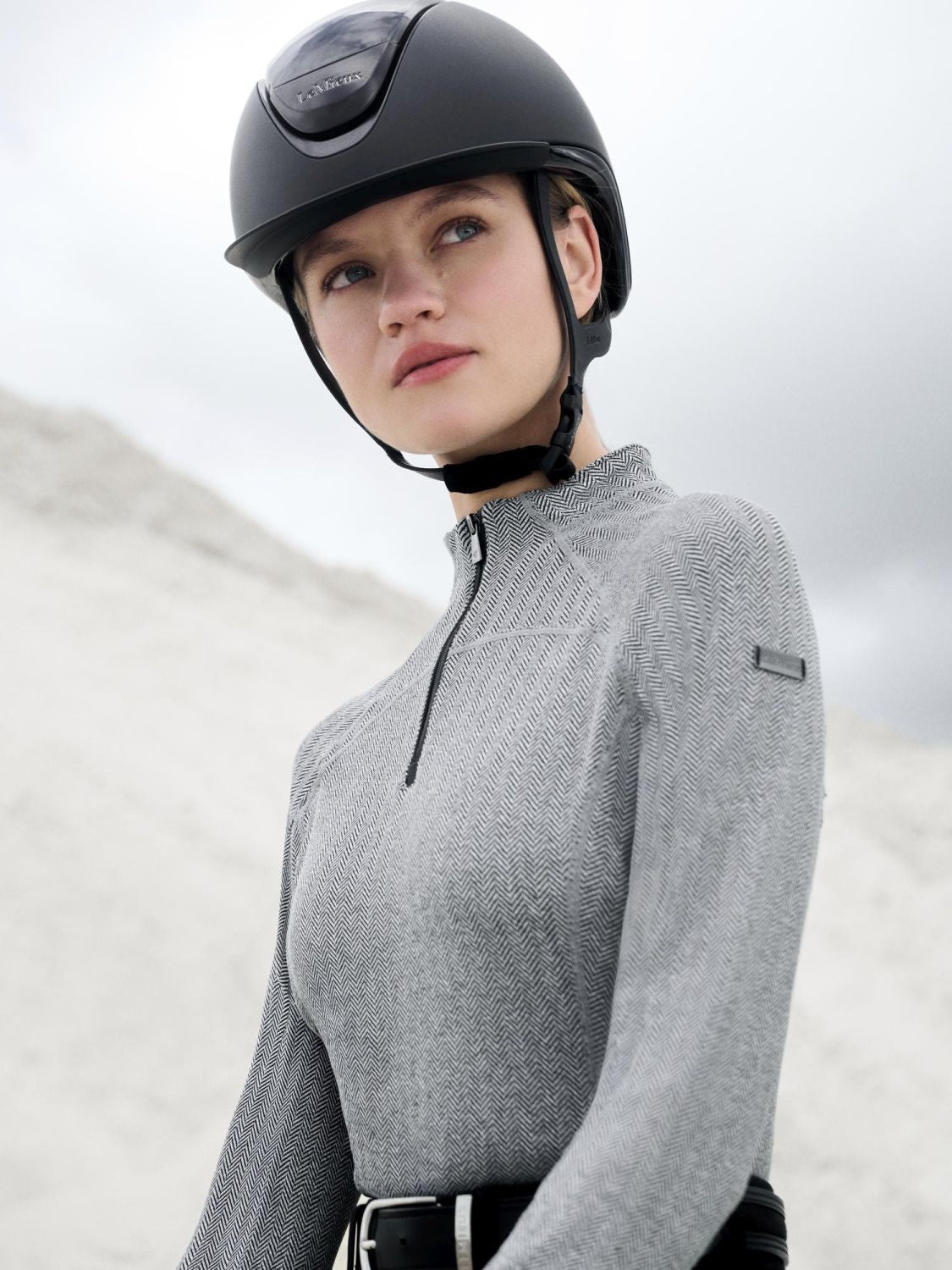 Reiterin trägt den LeMieux Base Layer Aspen Herringbone Black beim Reiten – elegante und funktionale Reitmode. Kombiniert mit schwarzer LeMieux Reithose.