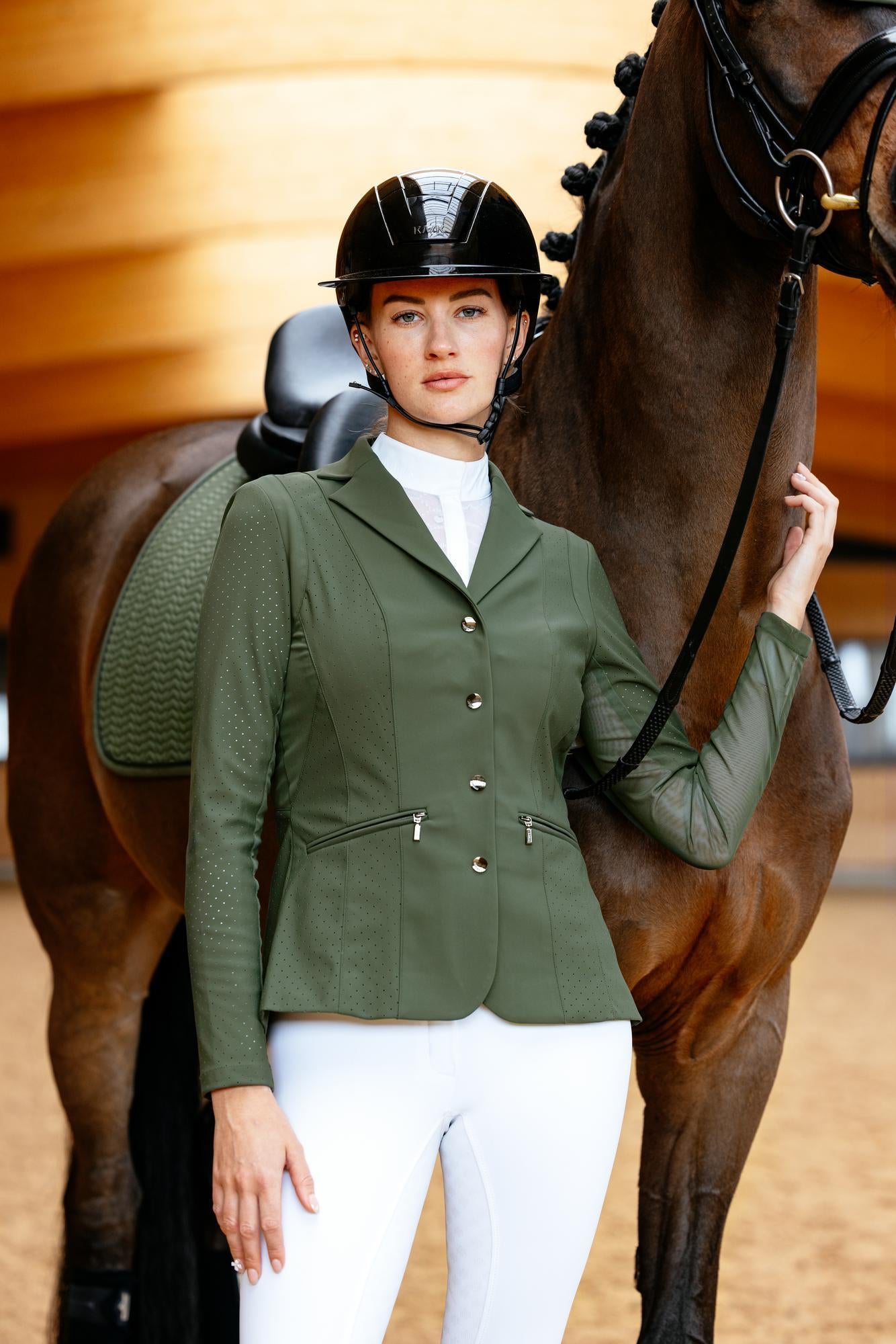 Nahaufnahme einer Reiterin im LeMieux Turnierjacket Jessica Mesh Pine Green vor der Prüfung. Modernes Turniersakko aus technischem Mesh-Material für Höchstleistungen im Dressurreiten, Springreiten und der Vielseitigkeit – klassisch elegante Turnierkleidung neu interpretiert.