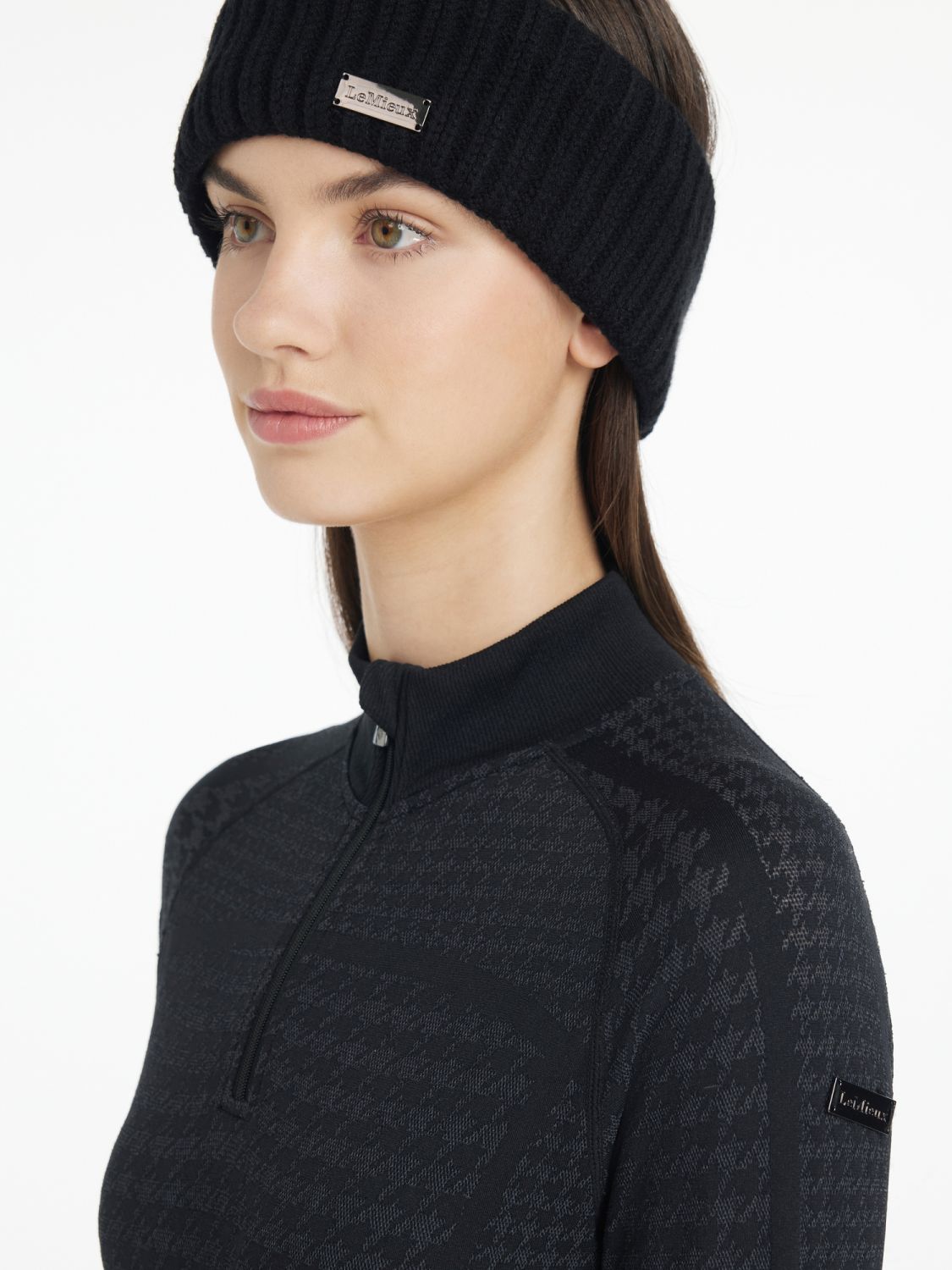 Seitliche Ansicht der Reiterin mit LeMieux Stirnband Aspen Schwarz – klassisches Stirnband mit Fischgrätmuster für stilvolle Reiterinnen. Das metallische LeMieux-Logo rundet das exklusive und stilvollen Design des Aspen Headbands in schwarz ab.