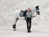 Reiterin neben weißem Pferd mit LeMieux Aspen Dressage Square Herringbone schwarz weiß Schabracke, elegante Dressurausstattung aus der LeMieux Aspen Kollektion.
