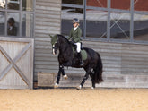 Reiterin galoppiert mit LeMieux Essence Dressage Square Pine Green, passender Fliegenmütze und Jessica Mesh Turnierjacket – Dressurschabracke in Aktion.