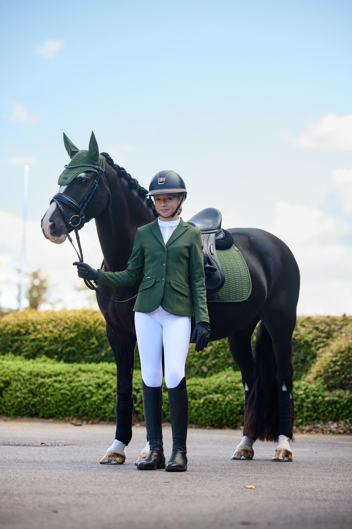 Jüngere Reiterin im Dressuroutfit mit LeMieux Essence Dressage Square Pine Green, Fliegenmütze und Jessica Mesh Turnierjacket – perfekte Outfit-Kombination für Turnier und Training.