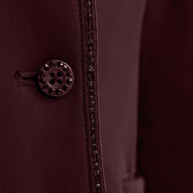 Detailaufnahme der Vorderseite mit dem edlen Knopfverschluss der Harcour Damen Turnierreitjacke Oria in Aubergine. Das Bild zeigt das harmonische Zusammenspiel der mit Kristallsteinen veredelten Knöpfe und der funkelnden Glitzerlitze, die das Reitsakko vom Kragen bis zum Saum rahmt. Diese hochwertige Verarbeitung der sichtbaren Knöpfe über dem Double-Closure-System ist eine Besonderheit der Turnierbekleidung für Reiterinnen, die ein exklusives und individuelles Turnieroutfit suchen.