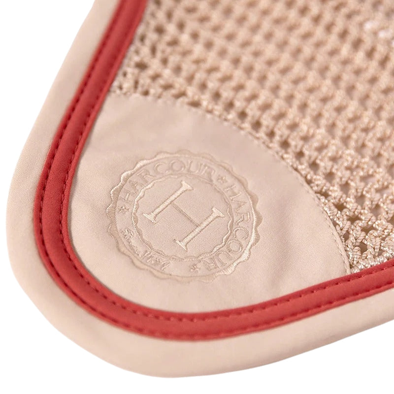 Detailaufnahme des Frontbereichs der Harcour Fliegenmütze Fredy Coquillage Shell. Zeigt das dezent eingestickte Harcour Logo in Beige und die kontrastfarbige Litze in Grapefruit. Exklusiver Fliegenschutz für Training und Turnier.