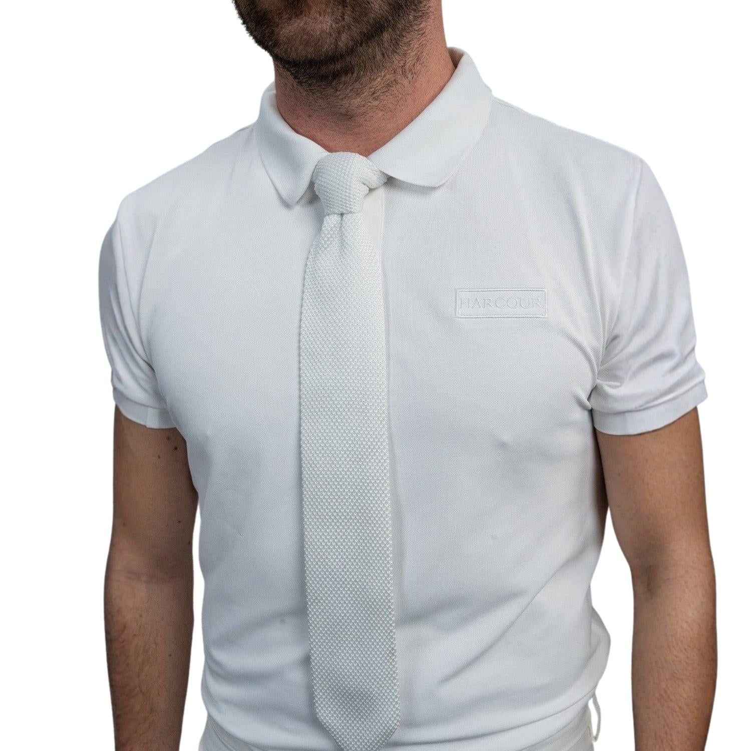 Detailansicht der weißen Harcour Herren Turnierkrawatte Corbi, perfekt kombiniert mit einem weißen Turnierpolohemd. Die vorgebundene Krawatte sitzt dank Easy-Close-System auch ohne Sakko präzise am Polokragen. Sportlich-elegante Turnierkleidung für warme Turniertage im Dressur- und Springsport.