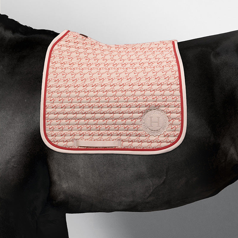 Edle Harcour Karembar Dressur Schabracke Jump Shell Grapefruit auf einem schwarzen Rappen. Das beige Außenmaterial (Shell) bildet einen luxuriösen Kontrast zum schwarzen Kurzhaar und Langhaar. Der anatomische Schnitt und die korallefarbene (Grapefruit) Litze betonen die Eleganz auf dem dunklen Pferd. Ideal für Dressursättel.