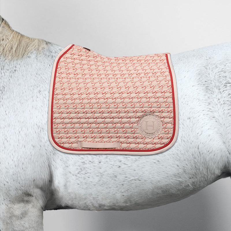 Frische Harcour Karembar Dressurschabracke Jump Shell Grapefruit auf einem weißen Schimmel. Die Kombination aus beigem Shell und korallefarbener Litze wirkt auf dem weißen Kurzhaar und Langhaar sommerlich und dynamisch. Der anatomische Schnitt im Widerristbereich sorgt für optimale Passform unter dem Dressursattel.