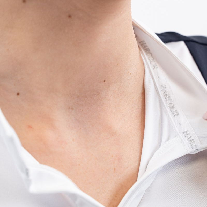 Die Detailaufnahme zeigt das Harcour Turniershirt Shine mit weit geöffnetem Stehkragen, wobei das Zusammenspiel von langem Frontreißverschluss und Magnetverschluss ein stressfreies An- und Ausziehen ohne Make-up-Flecken ermöglicht und an heißen Sommertagen eine praktische Abkühlung zwischen den Prüfungen bietet.