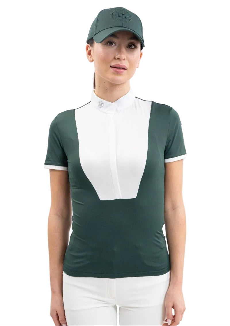 Eine Turnierreiterin trägt frontal das figurbetonte Harcour Turniershirt Shine in Jungle, bei dem der edle weiße Latz und der funkelnde Stehkragen mit Kristall-Logo einen klassischen Kontrast für das Dressurviereck bilden.