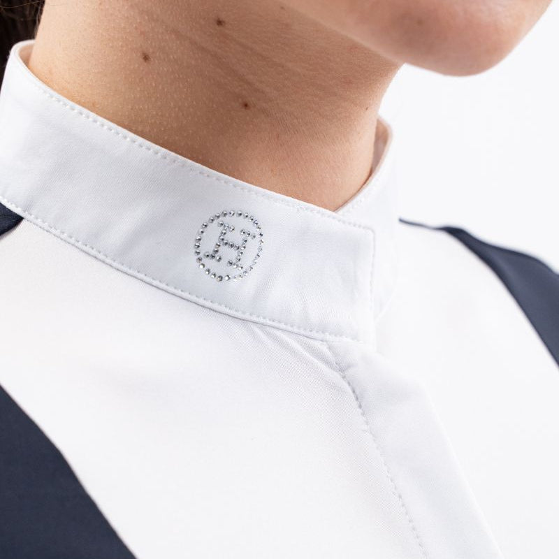 Detailansicht des Stehkragens am Harcour Turniershirt Shine Navy mit dem funkelnden Kristall-Glitzerlogo auf der rechten Halsseite, der elegant unter einem Turnierjacket oder Reitfrack hervorsteht und die innovative Funktion des Magnetverschlusses für ein einfaches Schließen andeutet.