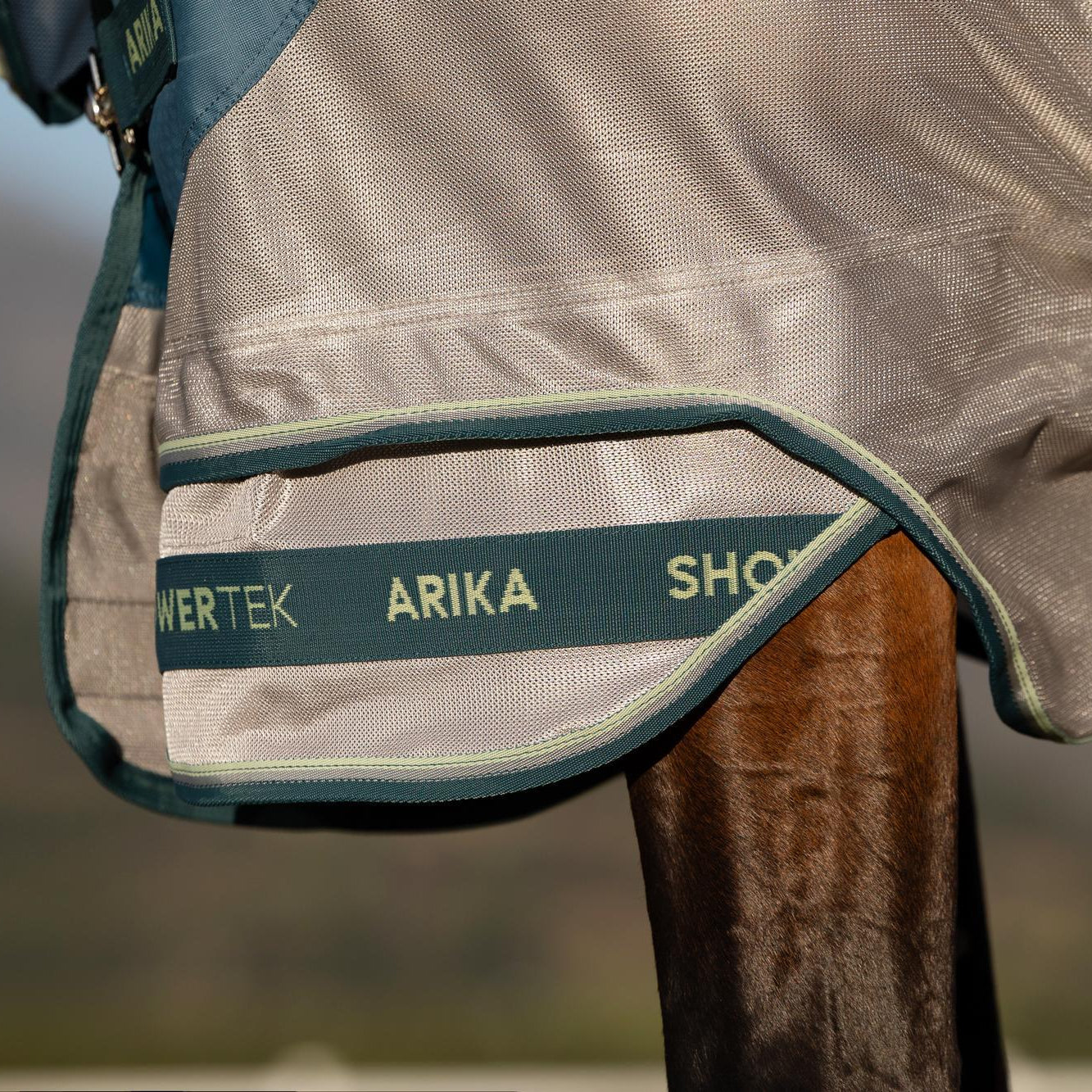 Die Detailaufnahme zeigt den zweiteiligen, patentierten Saum der LeMieux Hybriddecke mit Arika Shower-Tek Aufdruck, der den Vorderbeinen des Pferdes grenzenlose Bewegungsfreiheit für wilde Galoppaden und Bocksprünge auf der Koppel garantiert, ohne zu spannen.