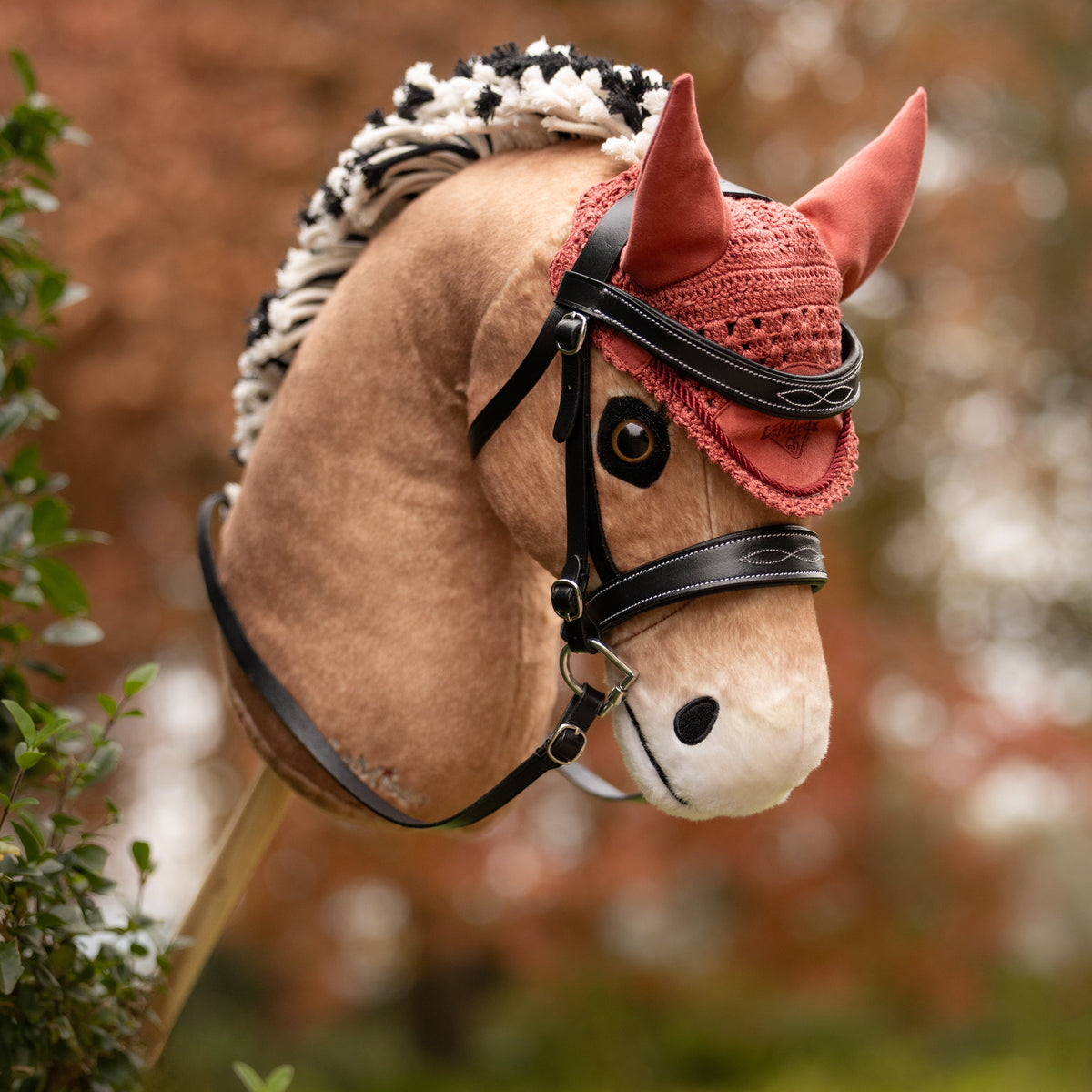 Detailansicht der altrosafarbenen LeMieux Hobby Horse Fliegenmütze Spiced Earth am Fjordpferd-Steckenpferd Oskar. Die gehäkelte Fliegenhaube bildet zusammen mit der schwarzen Trense ein stilvolles Zubehör-Set für Hobby Horsing Turniere und Ausritte.