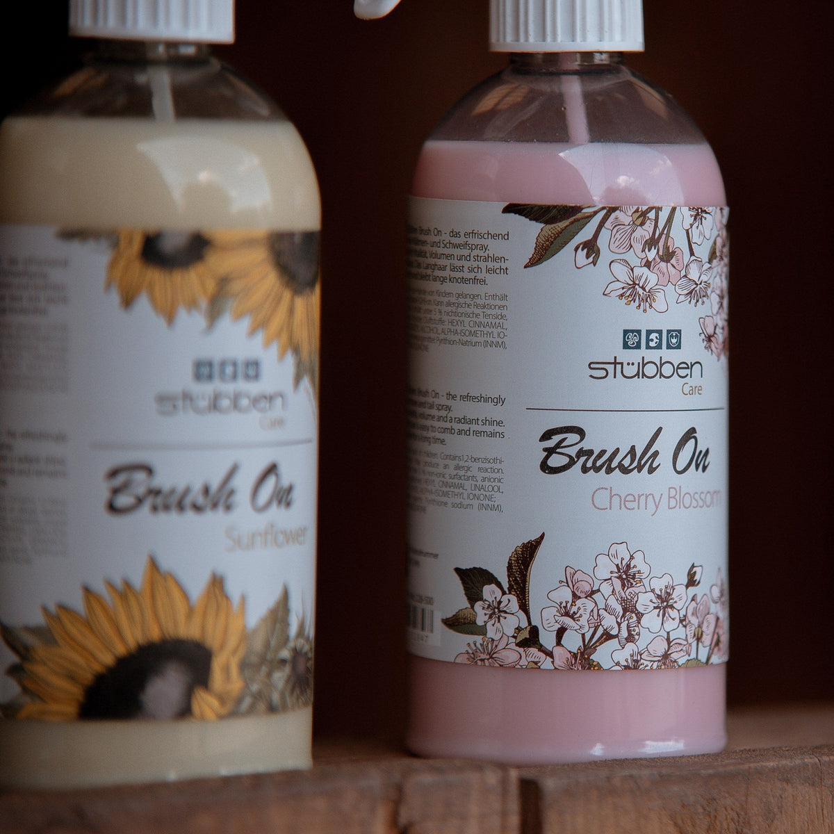 Stübben Care Brush On Sunflower und Cherry Blossom im Lifestyle-Foto vor dunklem Holzhintergrund. Mähnenspray für Pferde mit Sonnenblumen- und Kirschblüten-Design.