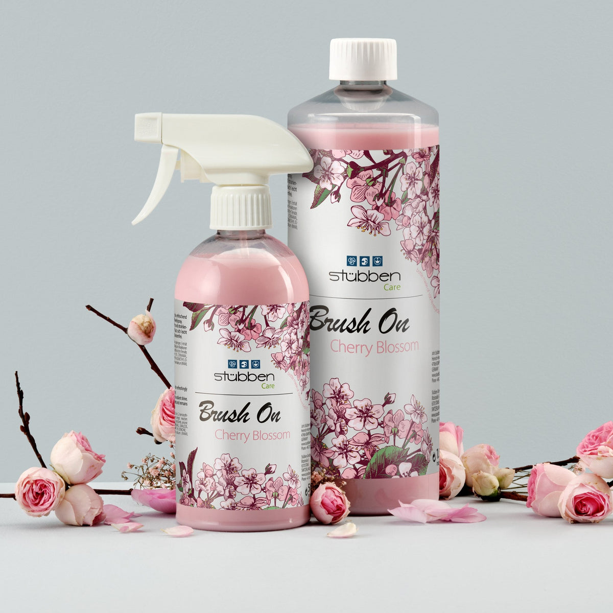 Stübben Brush On Cherry Blossom als 500 ml Sprühflasche und 1 Liter Nachfüllflasche im Stillleben mit Kirschblüten. Glanzspray für Mähne und Schweif zum Nachfüllen der Sprühflasche.