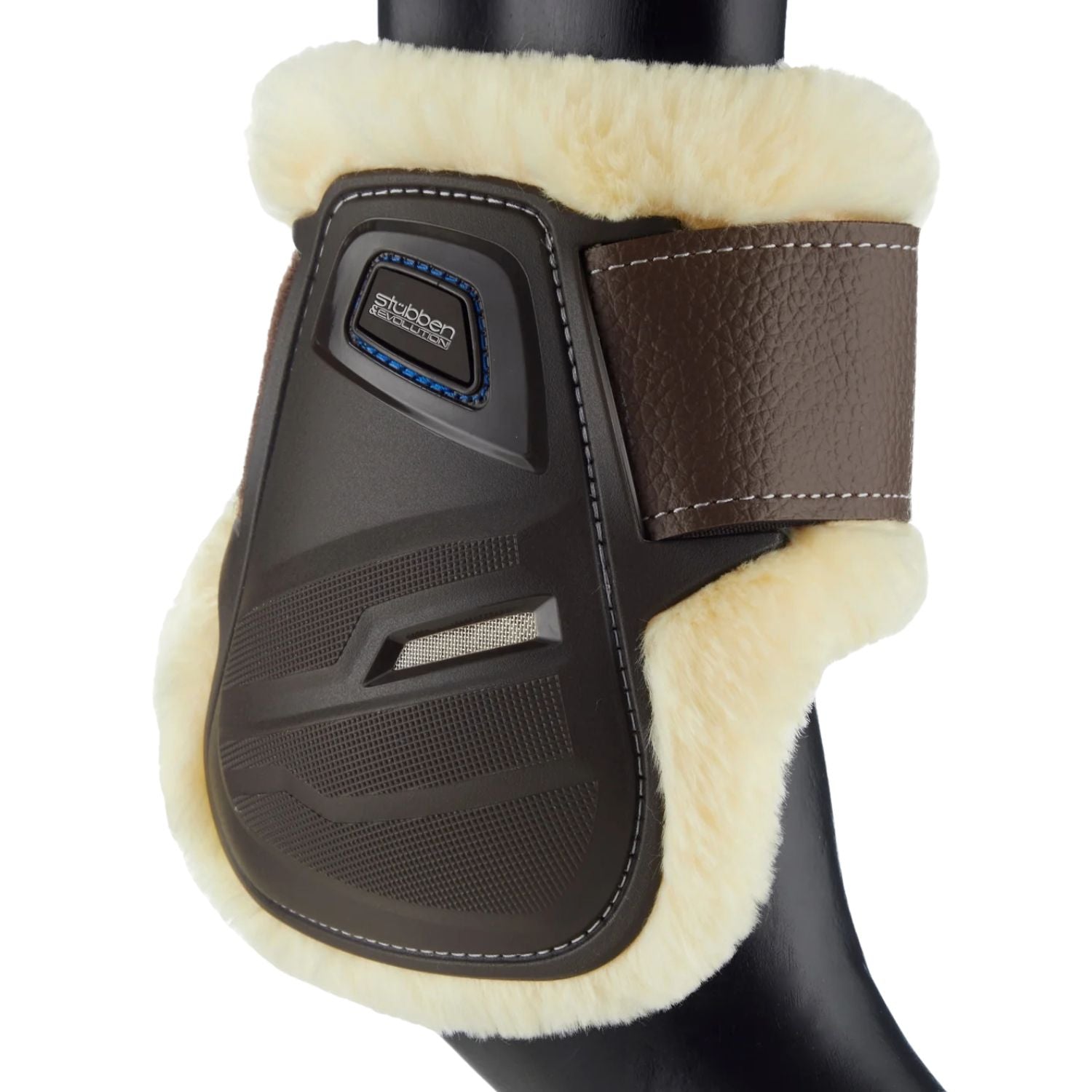 Diese braune Stübben Hybrid Streichkappe zeigt die funktionalen Lüftungsöffnungen im robusten Schlagschutz und einen edlen Farbkontrast zum tierfreundlichen Fleece-Fellrand, der sich für Tierliebhaber deutlich einfacher reinigen lässt als echtes Lammfell. Wo höchste Funktion auf exklusive Optik beim Beinschutz für die Hinterbeine trifft, lässt sich die Gamasche für ein harmonisches Gesamtbild ideal mit braunem Reitsportequipment wie eleganten braunen Stübben Trensen und braunen Sätteln kombinieren.
