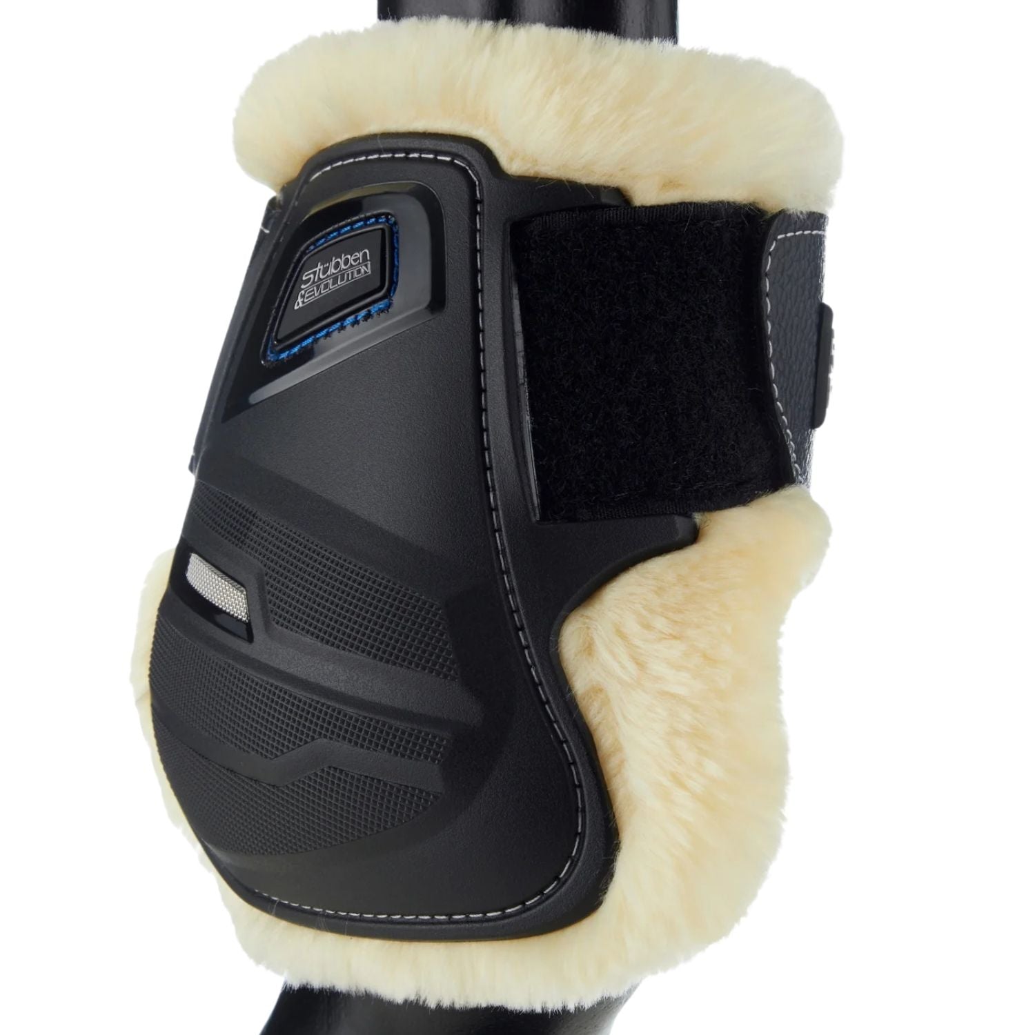 Diese schwarz weiße Stübben Hybrid Streichkappe zeigt die funktionalen Lüftungsöffnungen im robusten Schlagschutz und einen edlen Farbkontrast zum tierfreundlichen Fleece-Fellrand, der sich für Tierliebhaber deutlich einfacher reinigen lässt als echtes Lammfell. Wo höchste Funktion auf exklusive Optik beim Beinschutz für die Hinterbeine trifft, lässt sich die Gamasche für ein harmonisches Gesamtbild ideal mit schwarzem Reitsportequipment wie eleganten schwarzen Stübben Trensen und Sätteln kombinieren.