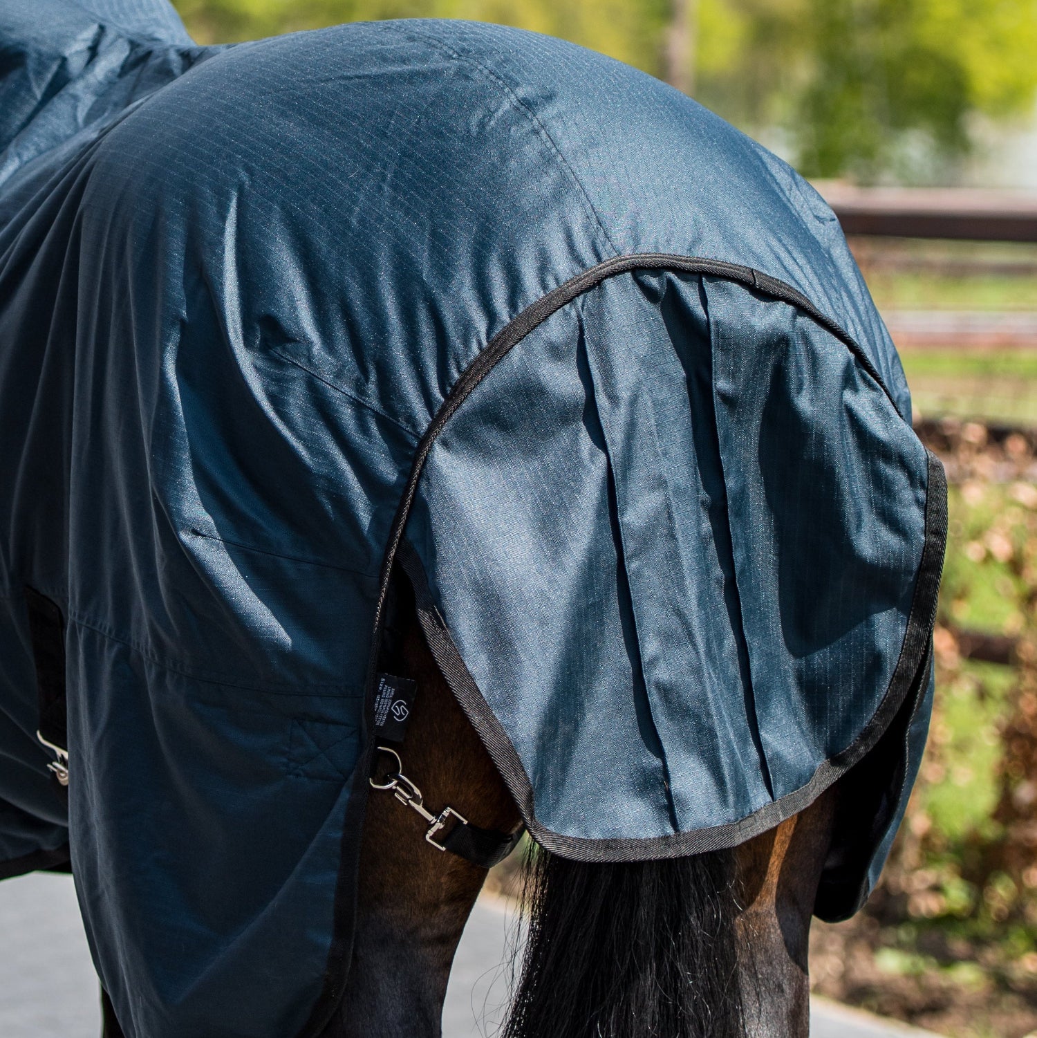 Diese Detailaufnahme der Trust Tetris Outdoordecke von hinten zeigt den großzügig geschnittenen Schweiflatz, der die empfindliche Schweifrübe des Pferdes zuverlässig vor Wind, Regen und extremer Kälte schützt, während er gleichzeitig volle Bewegungsfreiheit für eine natürliche Kommunikation und uneingeschränkte Bewegungsabläufe des Schweifes bei jeder winterlichen Witterung bietet.