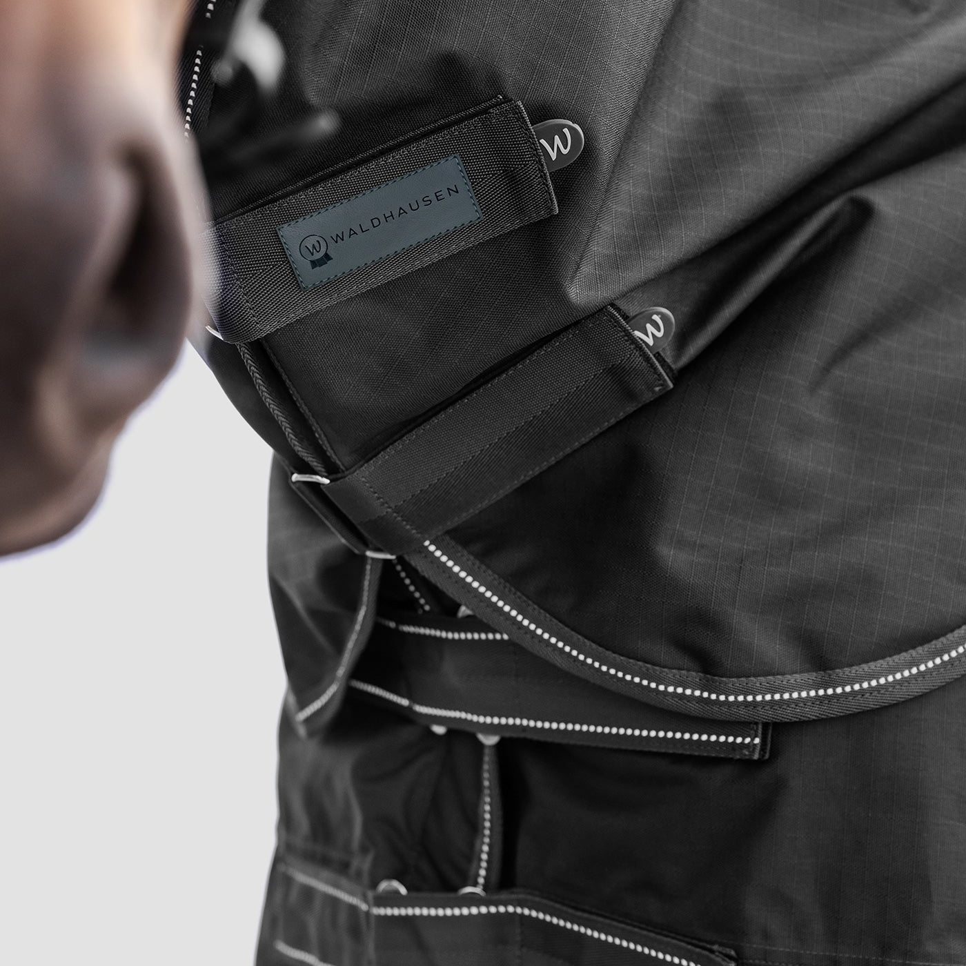 Detailaufnahme des Waldhausen Outdoorhalsteils in Schwarz am Pferdehals. Der Fokus liegt auf den zwei verstellbaren Klettverschlüssen zum einfachen Öffnen, Schließen und präzisen Anpassen der Passform für Pony und Pferd.