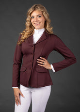 Reiterin trägt das Harry’s Horse Turnierjacket Crystal in Bordeaux zusammen mit weißer Turnierreithose und einem passenden Turniershirt. Der kurze, taillierte Schnitt des Jackets bietet maximale Bewegungsfreiheit und eignet sich ideal für Turnierreiterinnen, Reitprofis und Reitabzeichenprüfungen. Das Outfit vereint Stil, Komfort und klassische Turnieroptik.