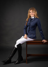 Reiterin sitzt entspannt und trägt das Harry’s Horse Turnierjacket Crystal in Navy geschlossen, kombiniert mit weißer Turnierreithose und passendem Turniershirt. Das Jacket zeigt seine körpernahe, taillierte und feminine Schnittform und passt sich den Bewegungen der Reiterin beim Sitzen perfekt an. Ideal für Damen Turnierreiterinnen, Dressurreiterinnen und Reitabzeichenprüfung, die ein elegantes und funktionales Turnieroutfit suchen.