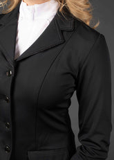 Das Detailbild zeigt die Glitzerpaspelierung am Kragenrand des Turnierjackets Sparkle und am oberen Rand der Klapptaschen von vorne. Die Rückseite des Jackets ist nicht zu sehen. Harrys Horse spielt mit edlen Details mit Glitzereffekt, ohne dabei zu übertreiben oder das klassische Bild der Turnierreitkleidung zu stören. Das Turnierjacket Sparkle ist modern, körpernah geschnitten mit Stretchmaterial für Bewegungsfreiheit.