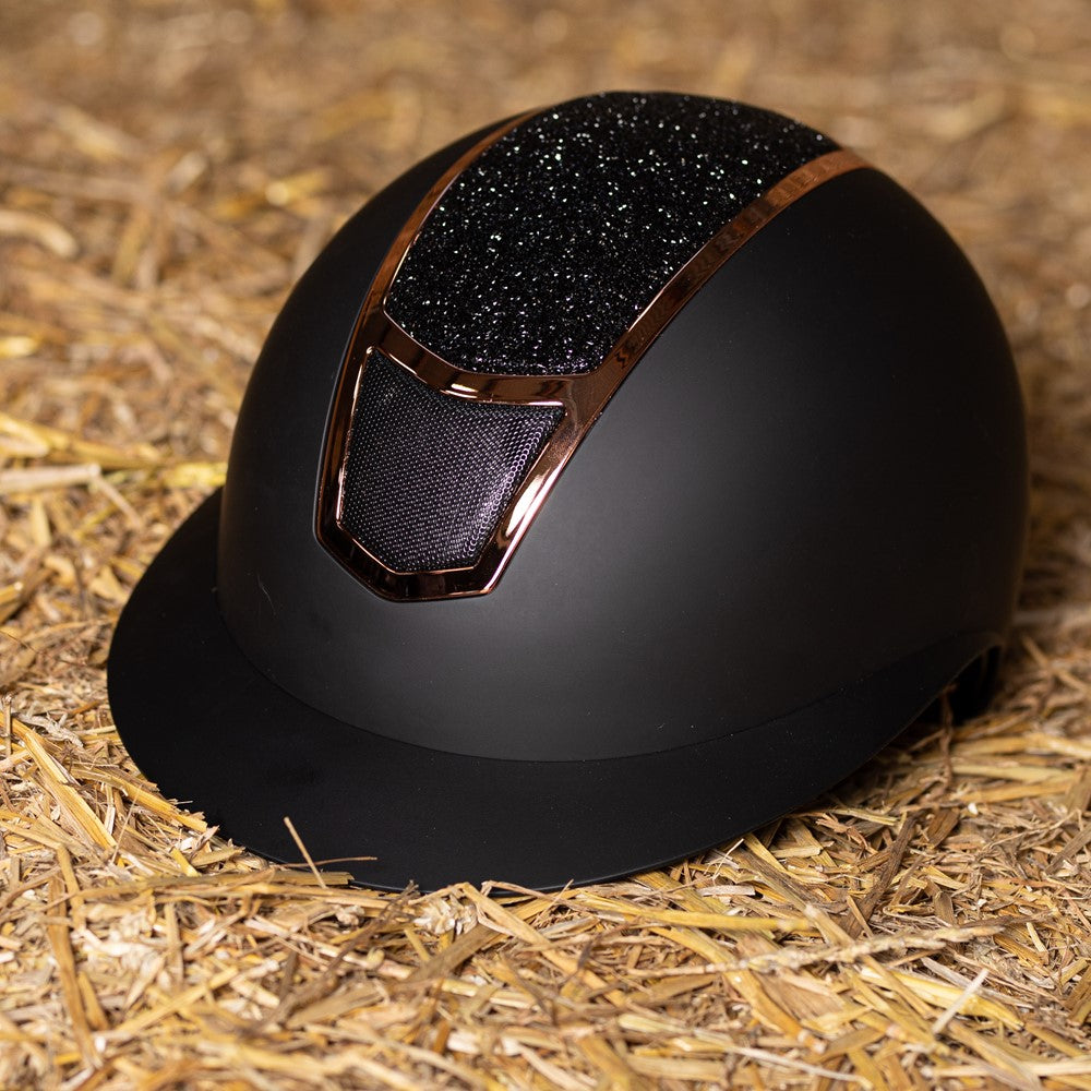 Harry’s Horse Mont Blanc Sparkle Reithelm in Schwarz Rosegold im Heu-Lifestyle-Setting, funkelnder Crystal-Rocks-Glitzer sichtbar, eleganter Sicherheitsreithelm für Turnier- und Freizeitreiterinnen.