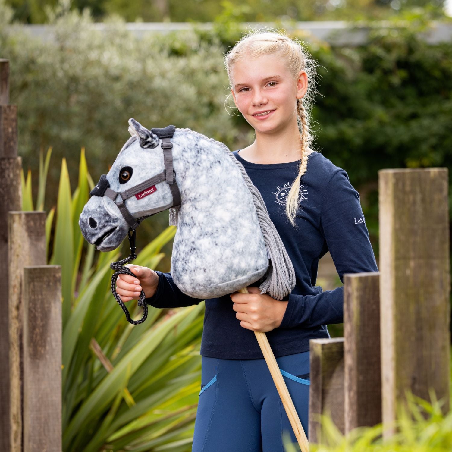 Das Hobby Horse Sammy wird von einem Mädchen am Halfter geführt. Der Pferdekopf wirkt durch die liebevollen Details realistisch. Zum Spielen uns Spaßhaben. Der Holzstab sorgt für Stabilität.