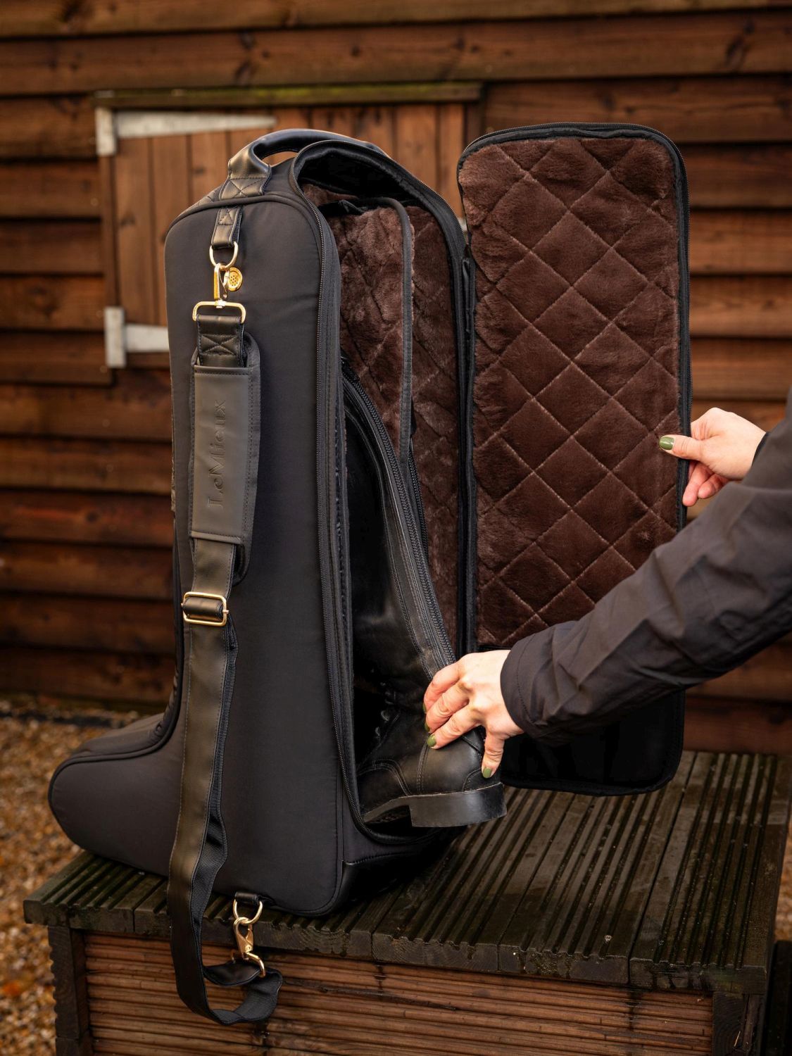 Offene LeMieux Luxe Stiefeltasche, in die eine Reiterin schwarze Reitstiefel stellt – luxuriöse Aufbewahrungstasche für Dressur-, Spring- und Polostiefel.