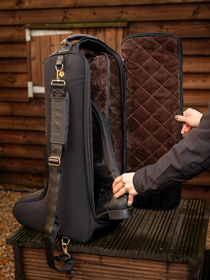 Offene LeMieux Luxe Stiefeltasche, in die eine Reiterin schwarze Reitstiefel stellt – luxuriöse Aufbewahrungstasche für Dressur-, Spring- und Polostiefel.