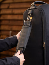 LeMieux Luxe Stiefeltasche mit abnehmbarem Schulterriemen und Schulterpolster – Reiterin hält den Trageriemen in den Händen, oben sichtbarer Handgriff.