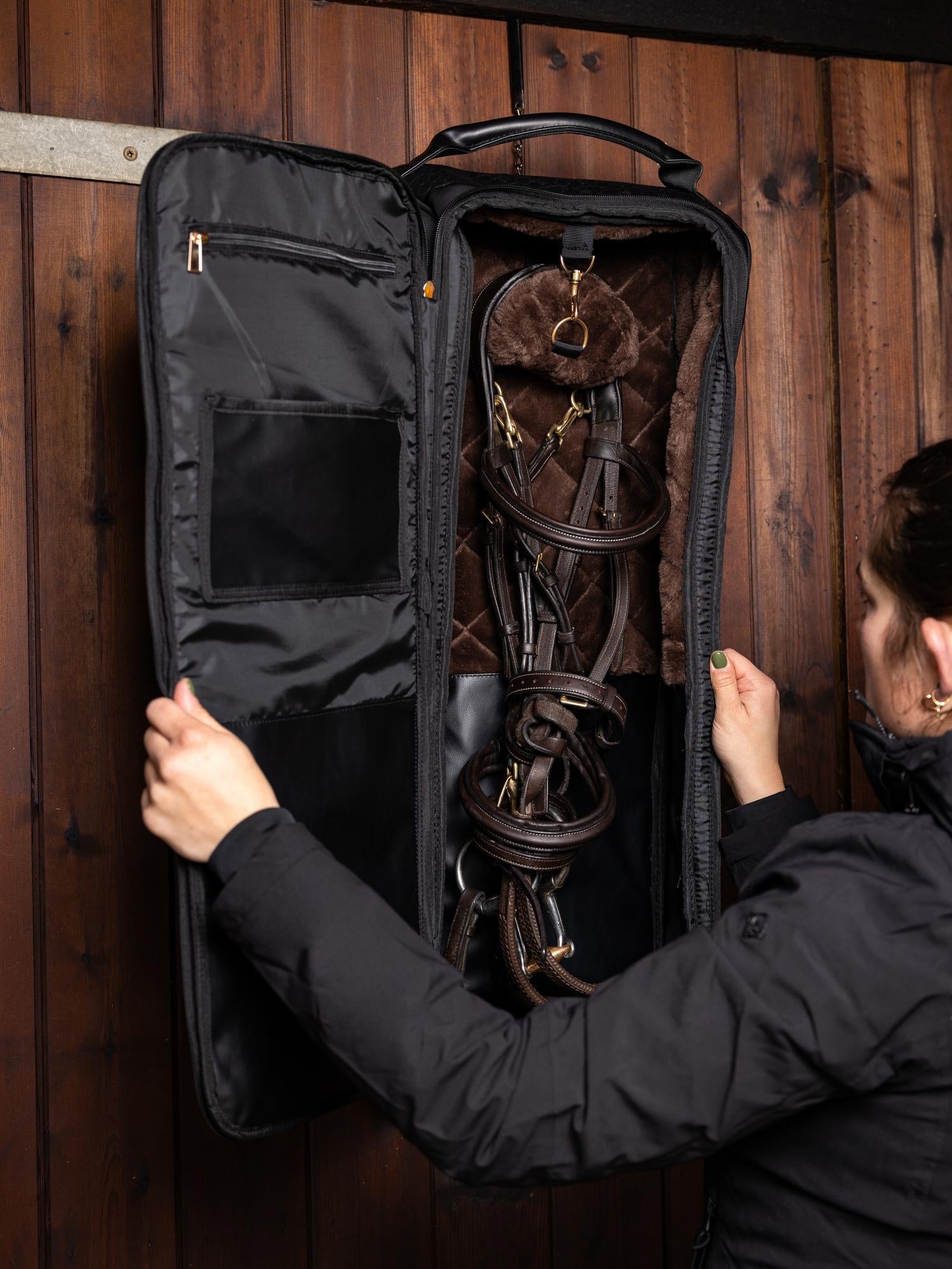 LeMieux Trensentasche Luxe Schwarz im Einsatz: Trense sicher aufgehängt im Stall, Lüftungsöffnungen verhindern Feuchtigkeit, praktischer L-Haken zum Aufhängen, perfekter Schutz von Zaumzeug auf Turnieren oder unterwegs, Teil der Luxe-Serie von LeMieux.