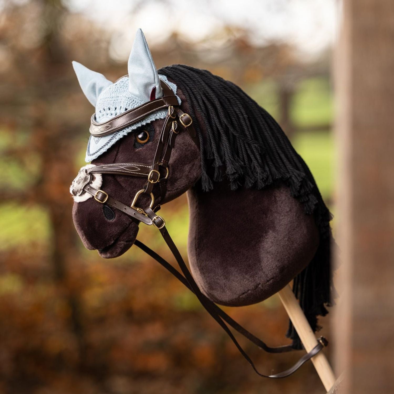 LeMieux Steckenpferd Hobby Horse Freya dunkelbraun, mit weichem Fell und realistischem Pferdekopf. Mit der mexikanischen Hobby Horse Trense Grackle und einer hellblauen Fliegenmütze in Hobby Horse Miniatur-Größe. Perfekt ausgestattet für das Traning mit Freya im Parcours. Die lange schwarze Mähne und die braunen Augen machen das Hobby Horse zu einem realistischen Abbild eines Pferdes.