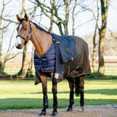 Ein Pferd trägt die LeMieux Unterdecke 200 g Navy mit darüberliegender LeMieux Arika Ripstop Turnout Rug Alpine. Das Bild zeigt, dass über der Unterdecke sowohl Stalldecken als auch Weidedecken getragen werden können. Es verdeutlicht die zahlreichen Variationsmöglichkeiten mit unterschiedlichen Füllungen für eine individuelle Temperaturanpassung. Ideal für Ponys oder Pferde mit verschiedenen Bedürfnissen, bietet Flexibilität, Komfort und optimalen Schutz bei allen Wetterbedingungen.