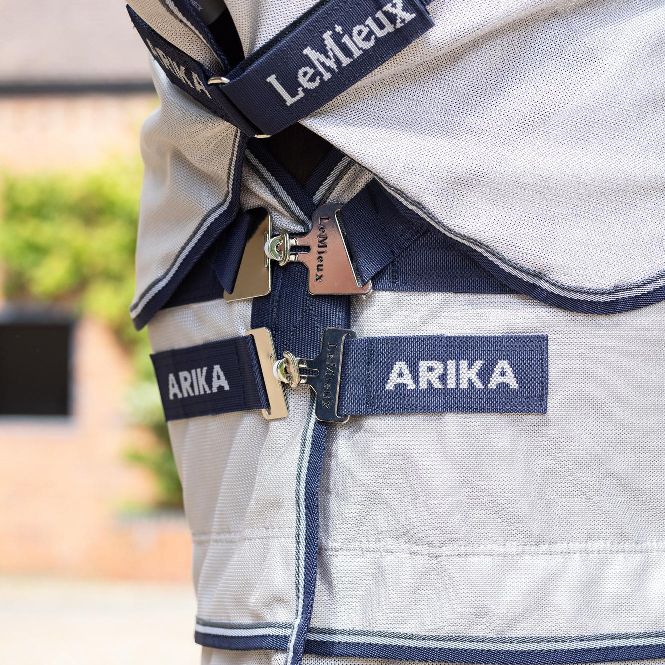 Detailaufnahme des innovativen T-Verschlusses der Arika Armour-Tek Fliegendecke in Grau, der um 45 Grad abgewinkelt ist, um Druckkräfte gleichmäßig auf die Brust des Pferdes zu verteilen und maximale Bewegungsfreiheit zu garantieren.