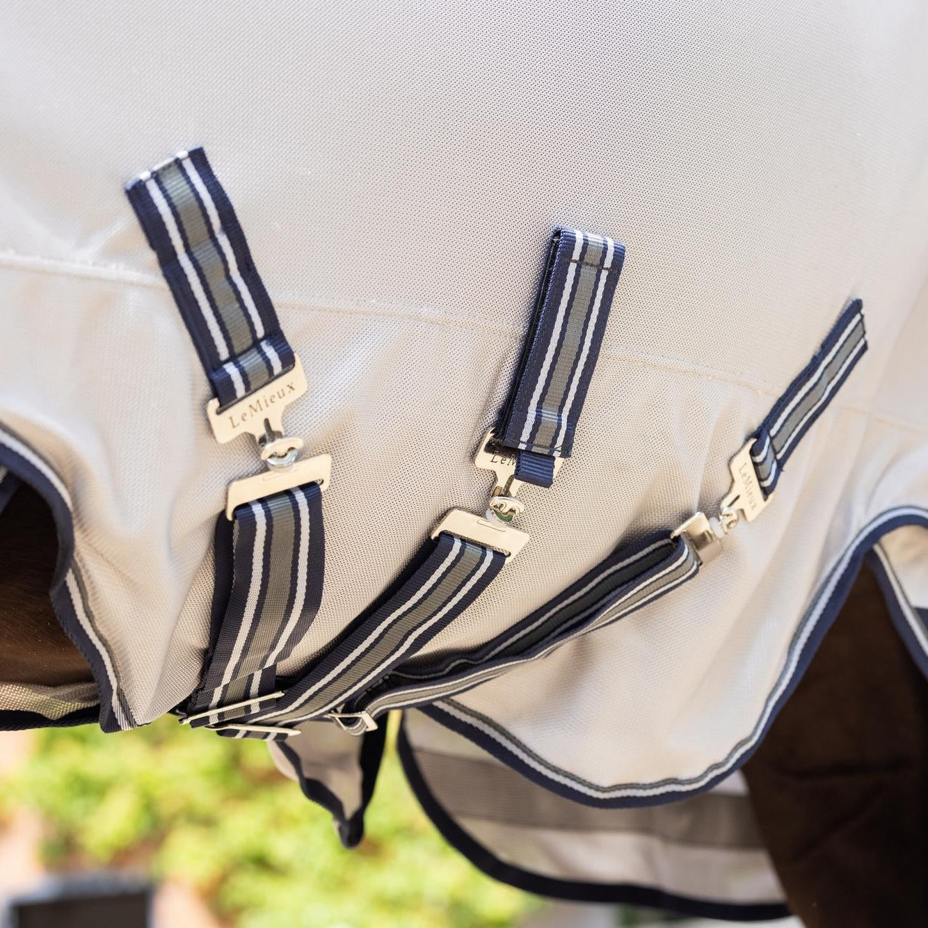 Nahaufnahme der Unterseite der LeMieux Fliegendecke mit dem großzügigen Bauchlatz zum Schutz der Bauchnaht sowie den drei flexibel verstellbaren Bauchgurten für einen sicheren und stabilen Sitz am Pferdekörper. Der mittlere Bauchgurt ist abehmar für mehr Flexiblität  beim mechanischen Fliegenschutz bei Pferden im Sommer.