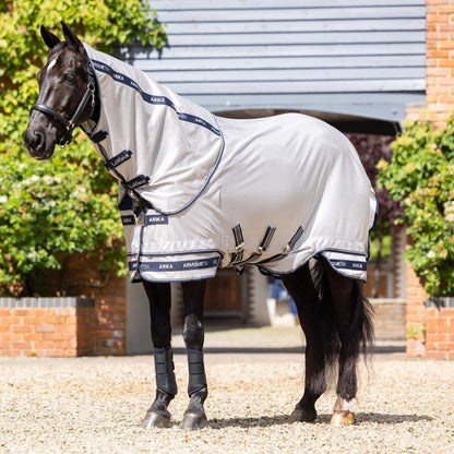 Ein schwarzer Rappe steht entspannt in der prallen Sonne mit der hellgrauen LeMieux Arika Armour-Tek Decke, die durch 85 % UV-Schutz und atmungsaktives Mikromesh die Temperatur reguliert und effektiv vor Insekten schützt. Die graue Fliegendecke ist bestens auch für heiße Sommertage geeignet.
