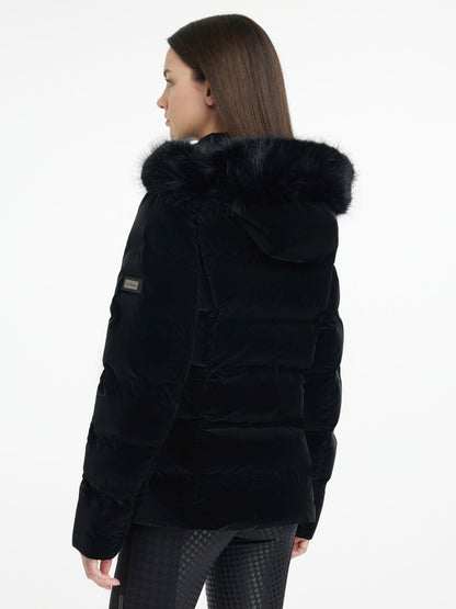 Rückansicht der LeMieux Aspen Puffer Jacket Black – taillierte schwarze Steppjacke mit abnehmbarer Kapuze. Model trägt die Steppjacke Aspen und zeigt diese in seitlicher Rückansicht. LeMieux Logo am Arm ist zu erkennen.