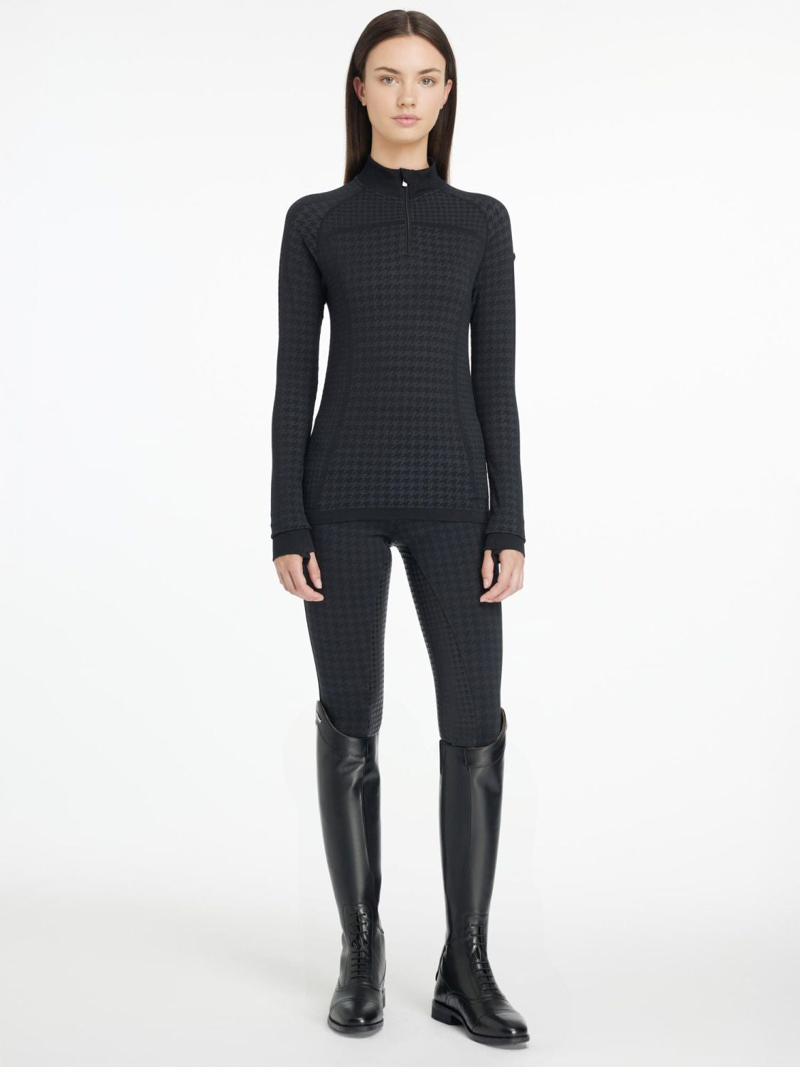 Das Model trägt das LeMieux Langarmshirt Quarter Zip Top Aspen Houndstooth kombiniert mit der Bregging Aspen Houndstooth black. Das Hahnentrittmuster geht vom Langarmshirt direkt in die Aspen Bregging über. Dazu können alle schwarzen Kleidungsteile der Capsual Kollektion Aspen kombiniert werden.