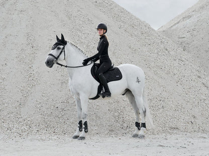 Reiterin trägt den LeMieux Aspen Houndstooth Quarter Zip Top Black beim Reiten – stylisches und atmungsaktives Reitshirt. Kombiniert mit anderen Kleidungsteilen aus der Aspen Kollektion Houndstooth im Hahnentrittmuster von LeMieux. 