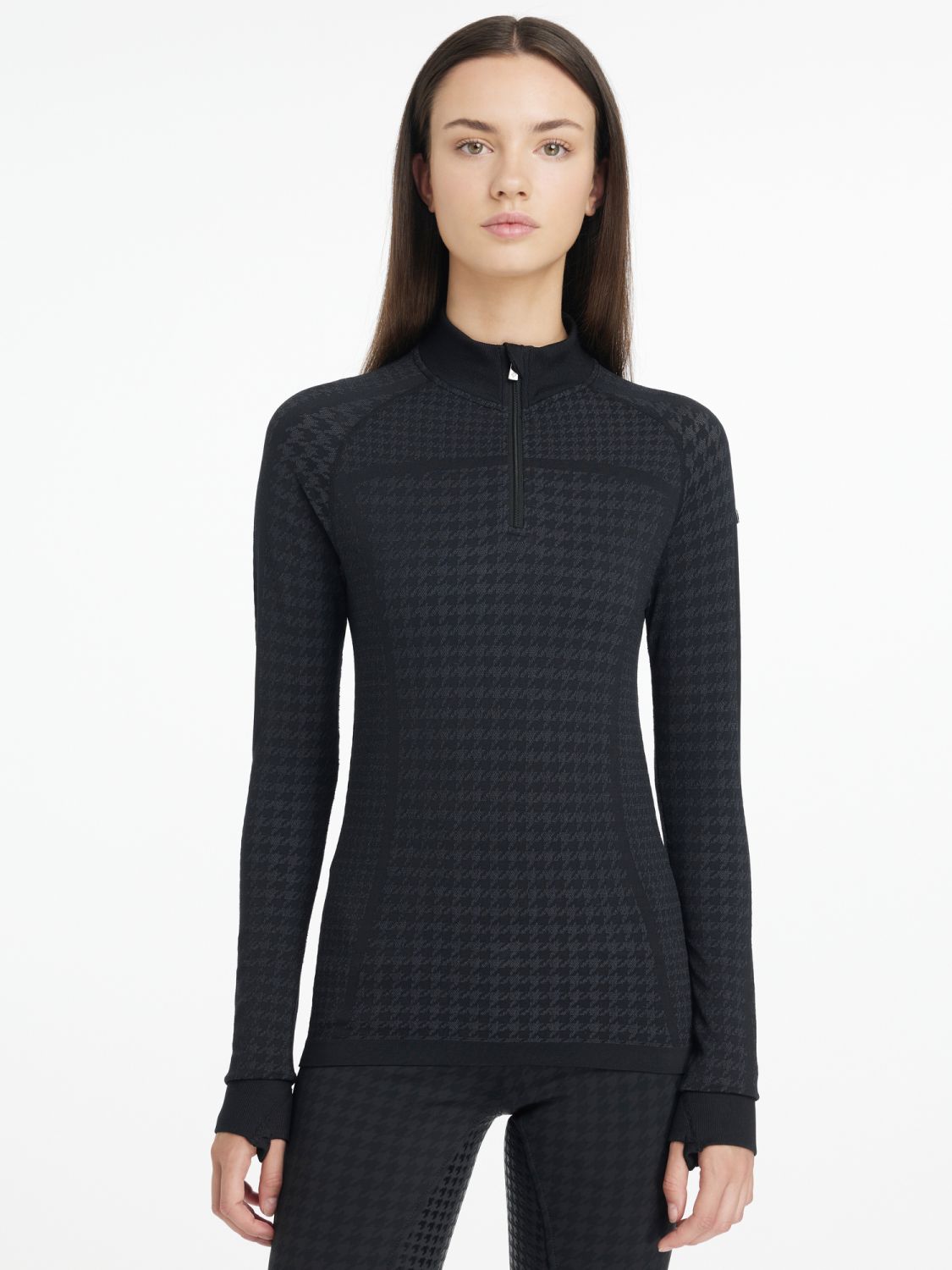 Model trägt den LeMieux Quarter Zip Top Aspen Houndstooth Black im Studio -elegantes Damen Reitshirt mit Hahnentrittmuster. Daumenlöcher runden den sportlichen reitlook ab.