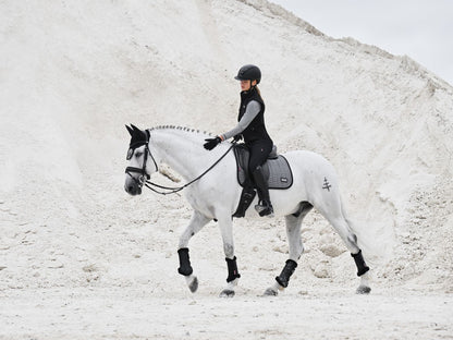 Pferd mit LeMieux Aspen Dressage Square Herringbone schwarz weiß Schabracke, Reiterin in Aspen Capsule Collection, elegante und funktionale Dressurausrüstung.