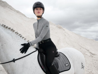 Reiterin mit Pferd in der LeMieux Aspen Kollektion – Schabracke Close Contact Square Herringbone Schwarz-Weiß. Elegante Springschabracke mit Lackpaspel und Velours-Einfassung, kombiniert mit LeMieux Reitoutfit für einen stilvollen, funktionalen Look im Springsport.