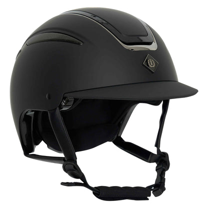 Der Imperial Riding Reithelm IRHOlania Deluxe Small Visor in Schwarz ist in der seitlichen Frontansicht zu sehen. Er besitzt eine matte Oberfläche, glänzende Chrom-Einsätze und das Imperial Riding Logo. Der schwarze Helmverschluss ist mit einem Kinnpolster ausgestattet, das für sicheren Halt beim Reiten sorgt.