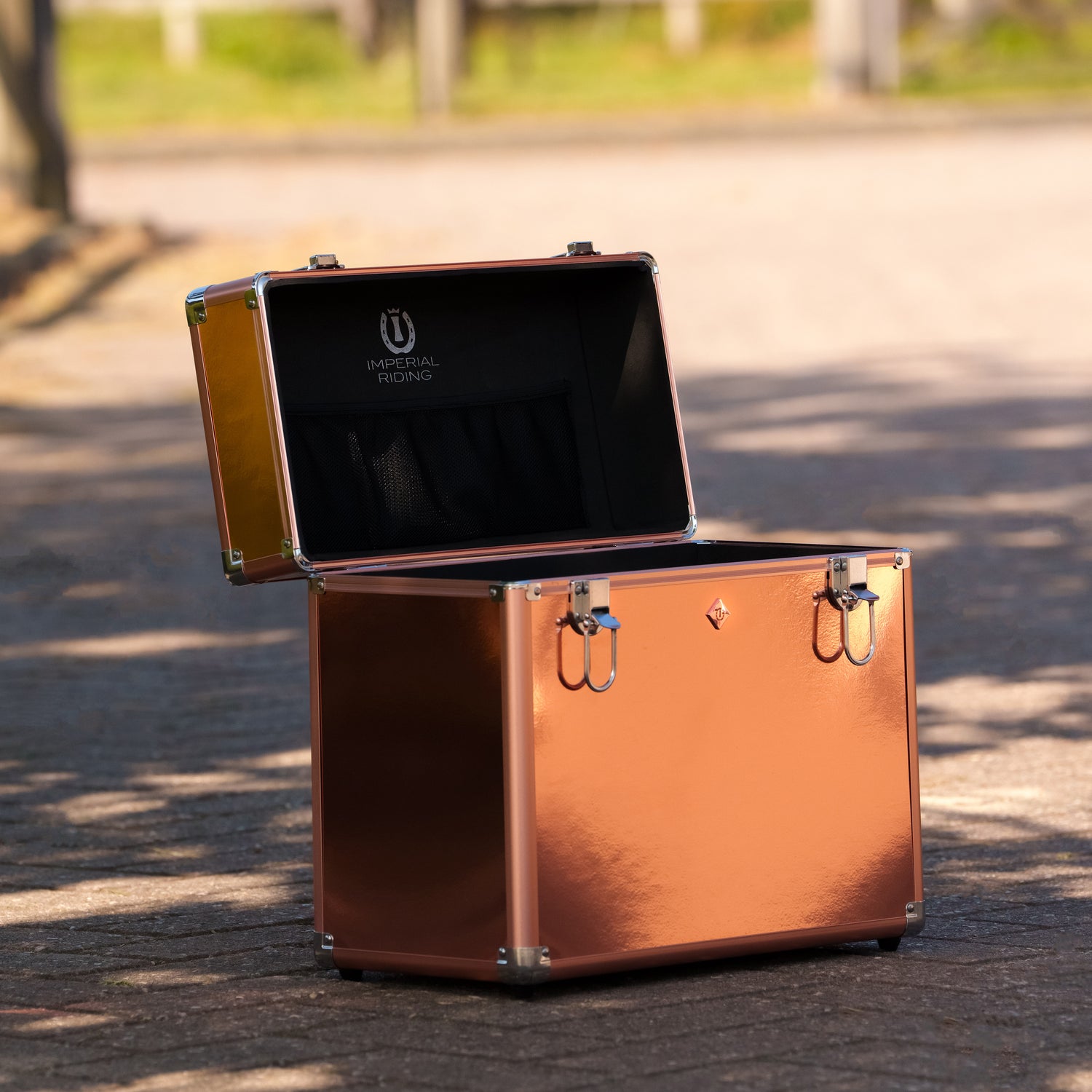 Die geöffnete roségoldene Imperial Riding Putzbox IRHBasic Slim Line glänzt im natürlichen Tageslicht und zeigt ihren großzügigen Innenraum ohne Trennwände, der viel Stauraum für Bürsten, Pflegemittel und Reitsportzubehör bietet – ideal für Stallalltag und Turniere.